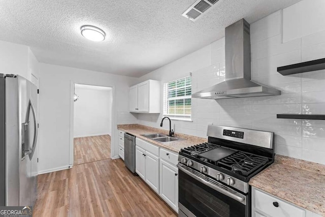 kitchen featuring wall chimney exhaust hood, sink, white cabinets, and stainless steel appliances