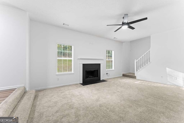 unfurnished living room featuring a wealth of natural light, light colored carpet, and ceiling fan