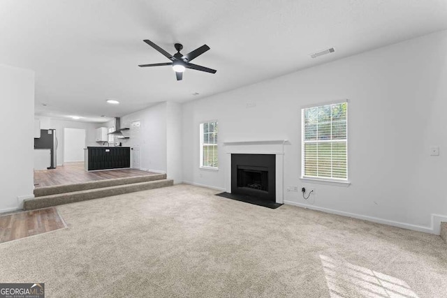 unfurnished living room featuring light colored carpet and plenty of natural light