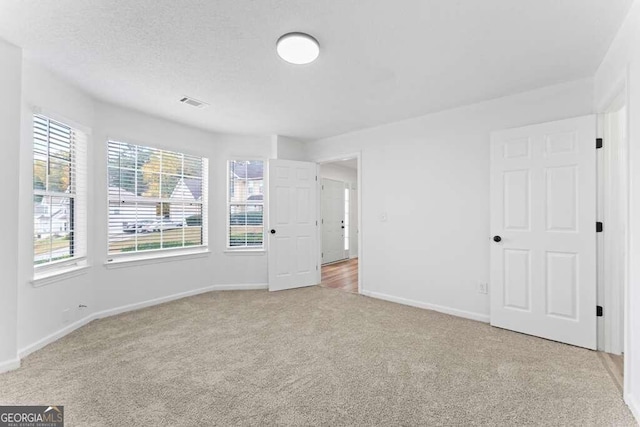 carpeted spare room with a textured ceiling