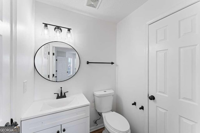 bathroom featuring vanity, toilet, and a textured ceiling