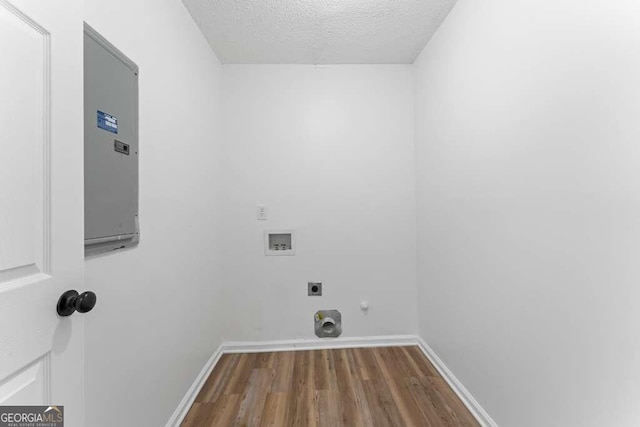 washroom featuring electric panel, a textured ceiling, wood-type flooring, hookup for a washing machine, and hookup for an electric dryer