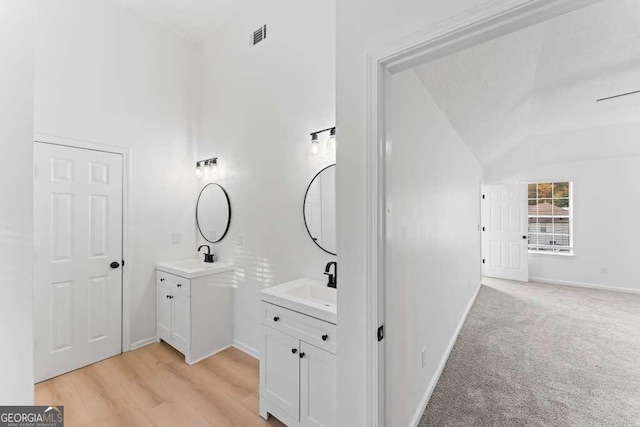 bathroom featuring vanity, hardwood / wood-style flooring, and vaulted ceiling