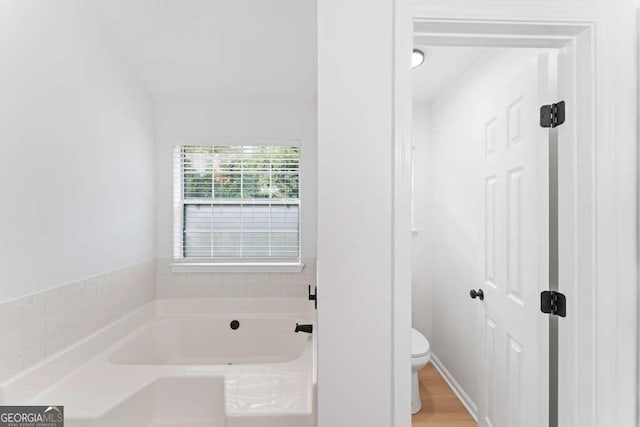 bathroom featuring hardwood / wood-style flooring, toilet, and a bathing tub