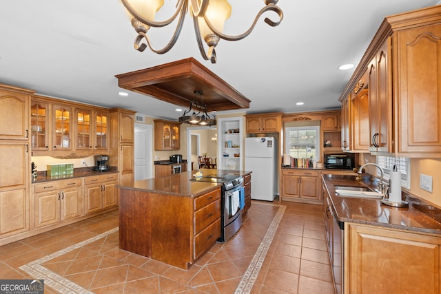 kitchen with dark stone countertops, sink, electric stove, white fridge, and a center island