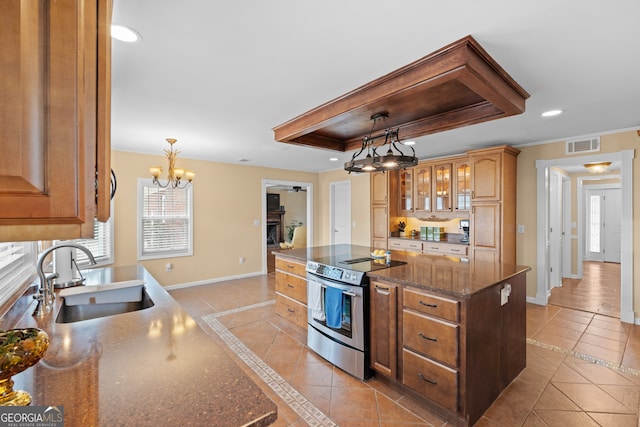 kitchen featuring hanging light fixtures, dark stone countertops, sink, electric stove, and a center island