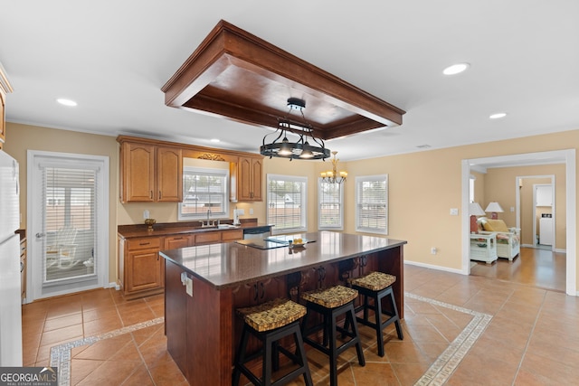 402 Brannen Dr, Statesboro, GA 30458 - kitchen featuring light tile patterned floors, a tray ceiling, baseboards, a center island, and a kitchen bar