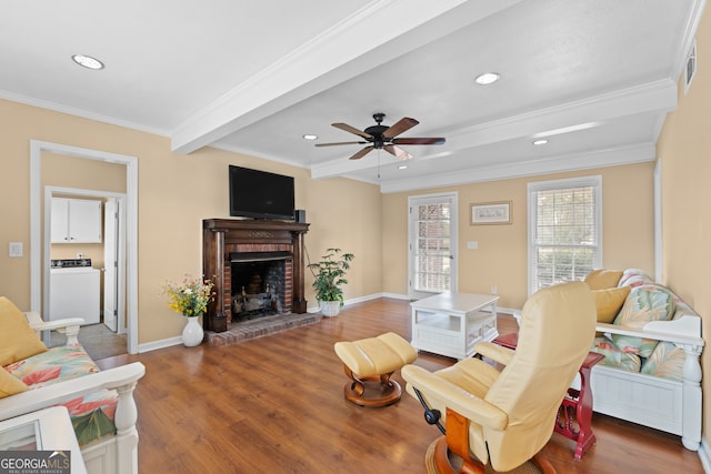 living room with washer / dryer, ornamental molding, wood-type flooring, and a brick fireplace