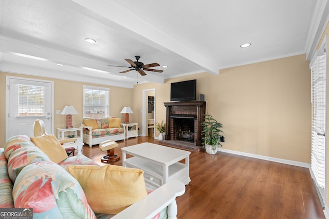 living room with hardwood / wood-style floors, ceiling fan, a brick fireplace, ornamental molding, and beamed ceiling