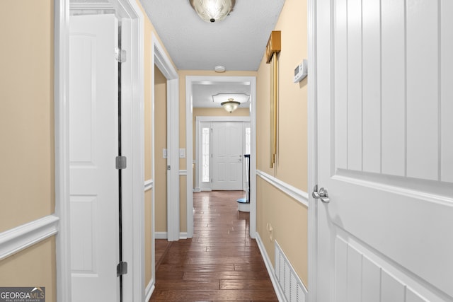 corridor featuring dark wood-type flooring and a textured ceiling