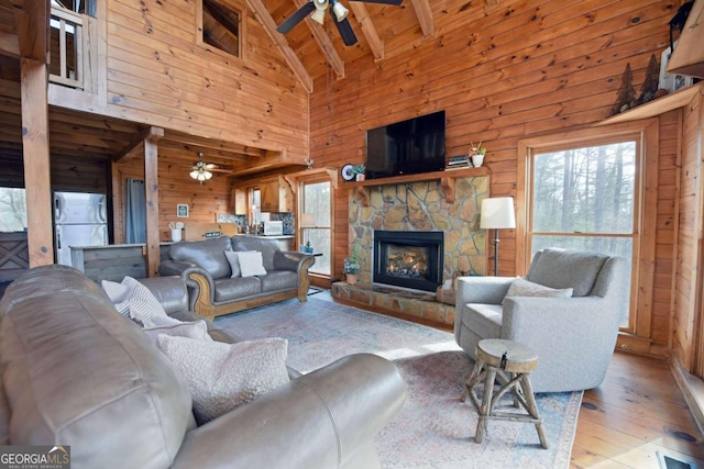 living room with beam ceiling, wooden walls, high vaulted ceiling, a fireplace, and wooden ceiling