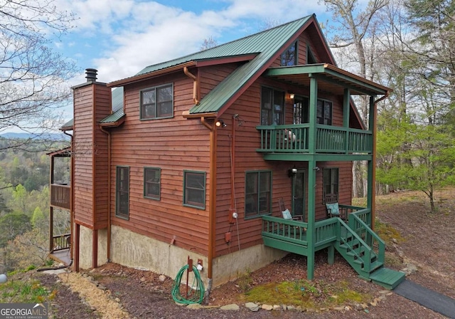 rustic home featuring metal roof, a chimney, and a balcony