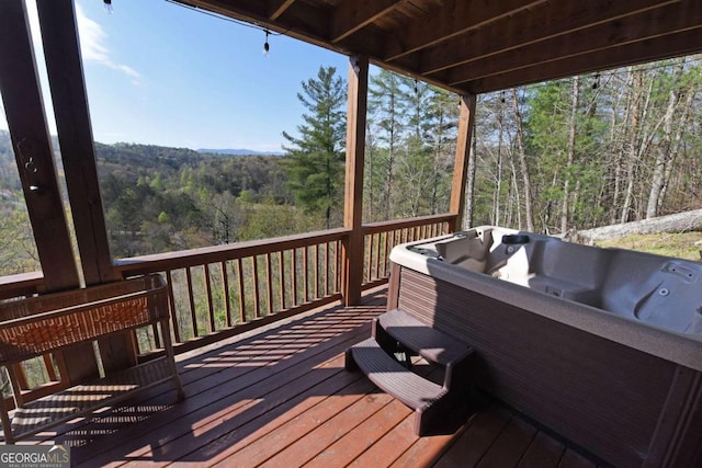 deck featuring a hot tub and a forest view