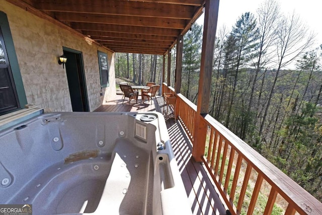 wooden terrace with a view of trees and a hot tub