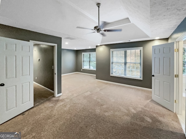 carpeted empty room with a textured ceiling, a tray ceiling, and ceiling fan