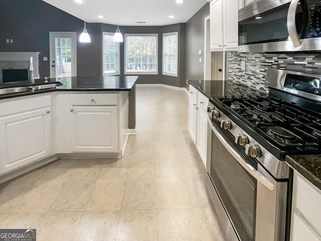 kitchen featuring backsplash, stainless steel appliances, hanging light fixtures, and white cabinets