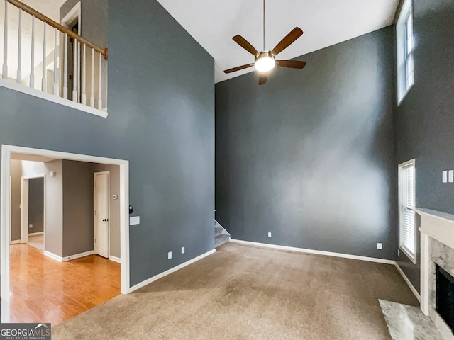 unfurnished living room with hardwood / wood-style flooring, high vaulted ceiling, and ceiling fan