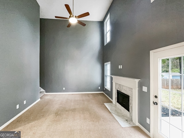 unfurnished living room with light carpet, a fireplace, high vaulted ceiling, and ceiling fan