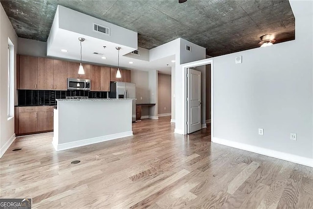 kitchen featuring tasteful backsplash, decorative light fixtures, a center island, appliances with stainless steel finishes, and light hardwood / wood-style floors