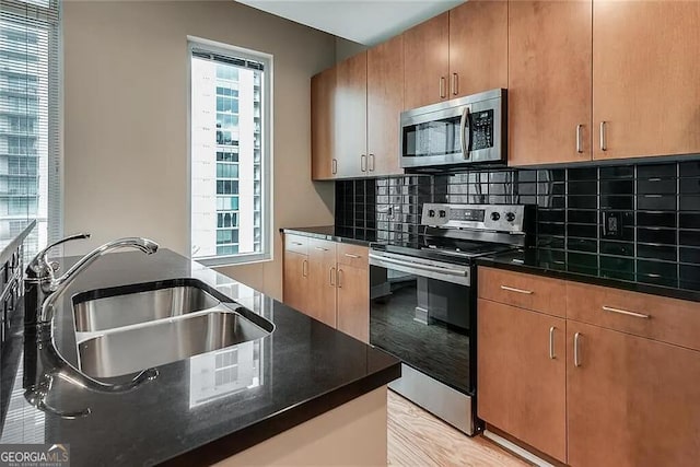 kitchen with tasteful backsplash, appliances with stainless steel finishes, sink, and dark stone countertops