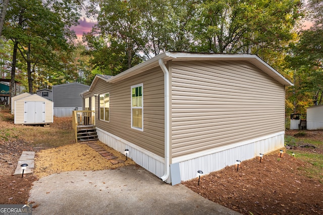 property exterior at dusk featuring a storage shed