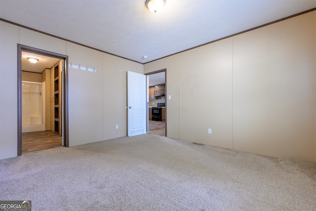 unfurnished bedroom with crown molding, carpet floors, and ensuite bathroom