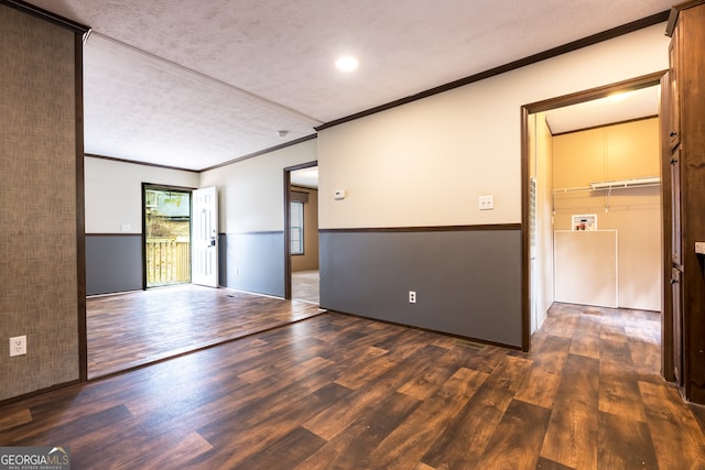 empty room with crown molding, a textured ceiling, and dark hardwood / wood-style floors