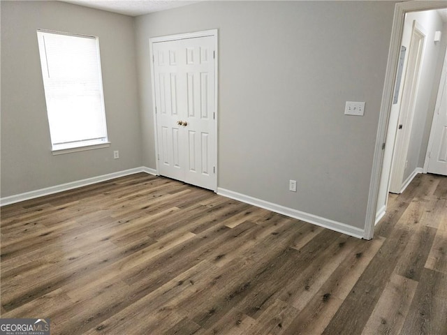 unfurnished bedroom featuring a closet, baseboards, and wood finished floors