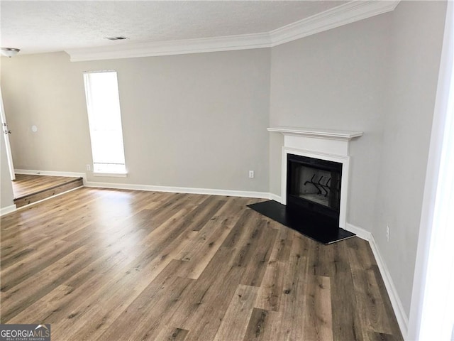 unfurnished living room featuring a fireplace with raised hearth, visible vents, ornamental molding, wood finished floors, and baseboards