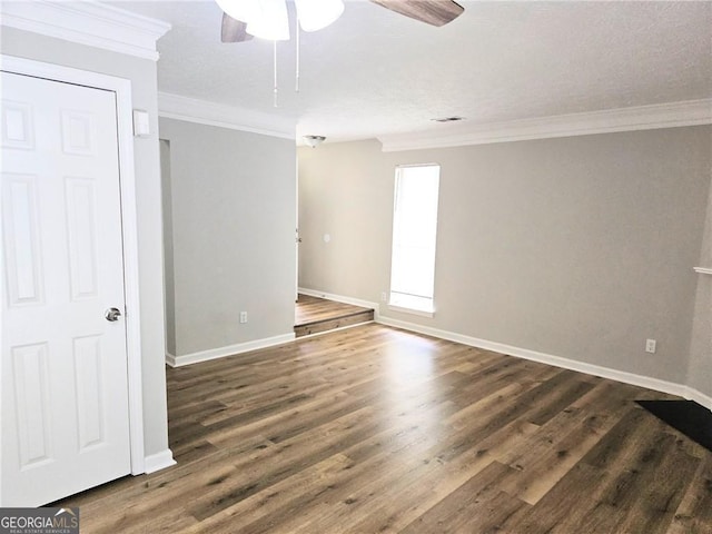 empty room featuring ornamental molding, baseboards, and wood finished floors