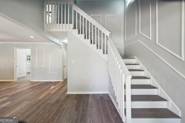 stairway featuring ornamental molding and wood-type flooring