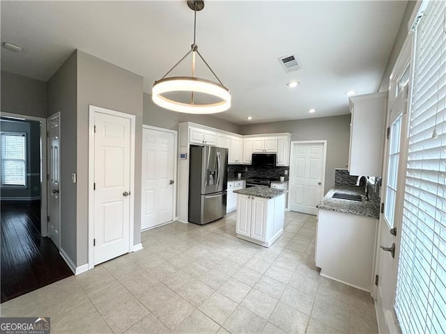 kitchen with a wealth of natural light, white cabinets, light stone counters, and appliances with stainless steel finishes