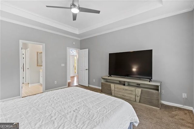 carpeted bedroom featuring a raised ceiling, ensuite bathroom, ceiling fan, and ornamental molding