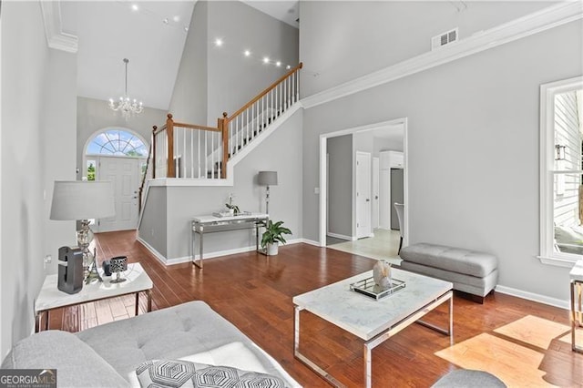 living room with a chandelier, wood-type flooring, high vaulted ceiling, and ornamental molding