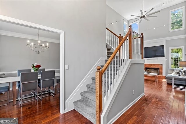 stairs featuring plenty of natural light, wood-type flooring, and ceiling fan with notable chandelier