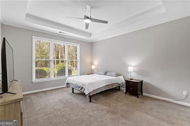 carpeted bedroom featuring a raised ceiling, ceiling fan, and crown molding