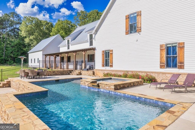 view of swimming pool featuring a patio area, a pool with connected hot tub, and fence