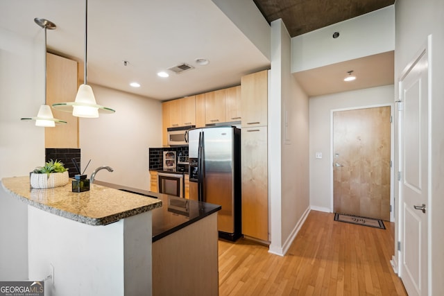 kitchen with light hardwood / wood-style flooring, kitchen peninsula, pendant lighting, light brown cabinetry, and appliances with stainless steel finishes