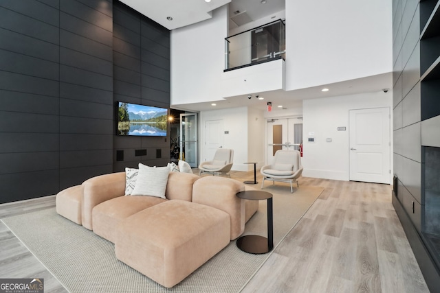 living room featuring a high ceiling, light hardwood / wood-style floors, and french doors