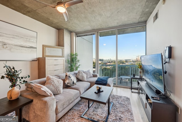 living room with a wall of windows, light hardwood / wood-style flooring, and a healthy amount of sunlight