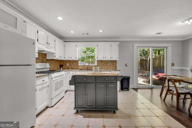 kitchen featuring a center island, white cabinets, light wood-type flooring, and white appliances