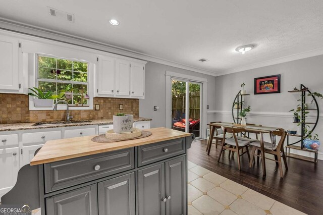 kitchen with hardwood / wood-style floors, sink, white cabinetry, and a healthy amount of sunlight