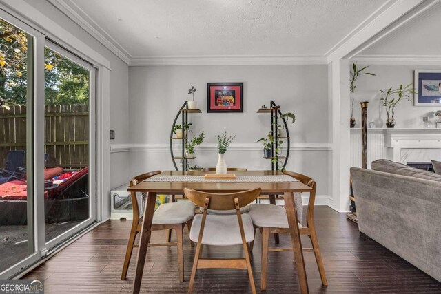 dining area featuring dark wood-type flooring, ornamental molding, and a textured ceiling