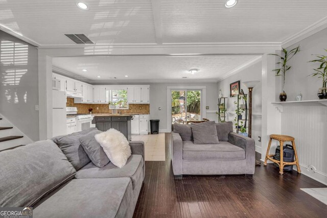 living room with crown molding, sink, and dark hardwood / wood-style flooring