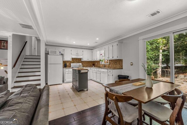 kitchen featuring white appliances, white cabinetry, and ornamental molding