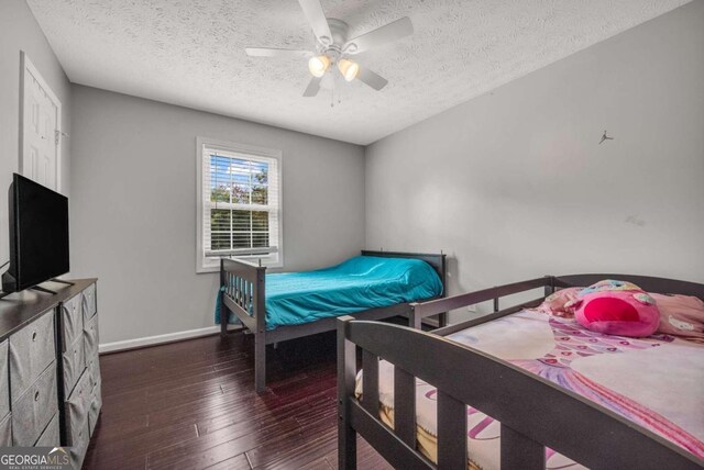 bedroom featuring dark hardwood / wood-style floors, a textured ceiling, and ceiling fan