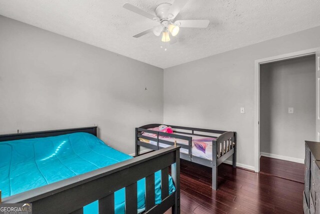 bedroom featuring dark hardwood / wood-style flooring, a textured ceiling, and ceiling fan