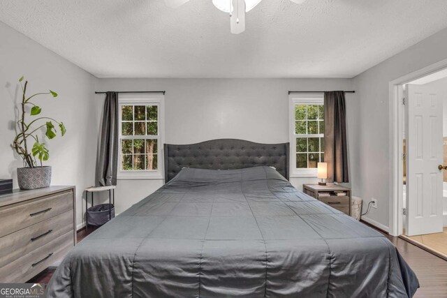 bedroom with hardwood / wood-style floors, multiple windows, a textured ceiling, and ceiling fan