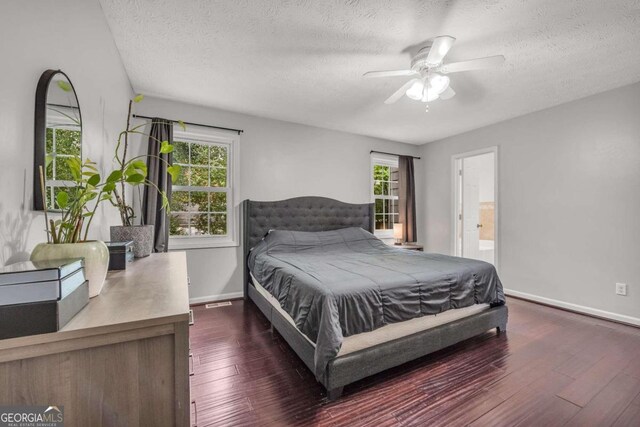 bedroom featuring ceiling fan, ensuite bath, a textured ceiling, and dark hardwood / wood-style floors