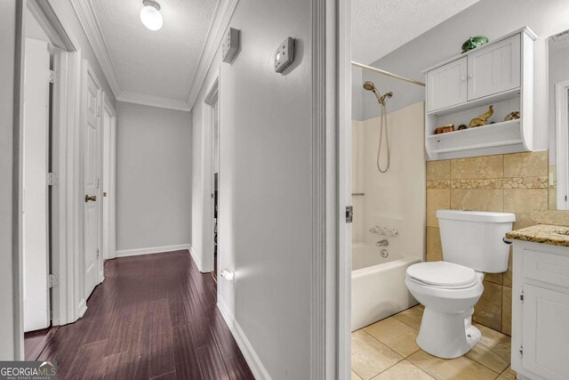 full bathroom featuring washtub / shower combination, toilet, vanity, hardwood / wood-style flooring, and ornamental molding